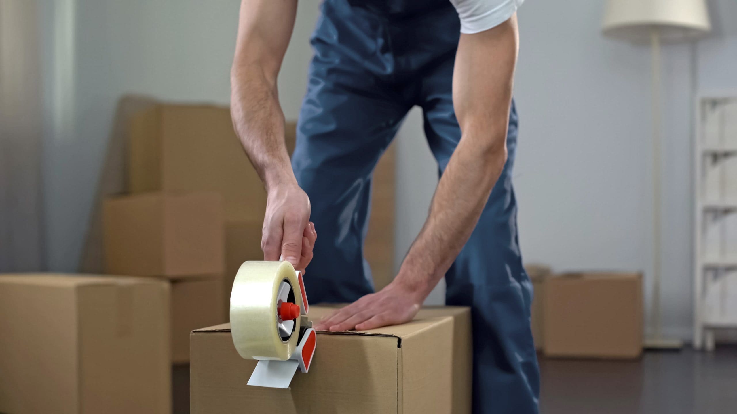 How To Spot A Moving Scam - Moving company worker packing cardboard boxes, quality delivery services - Mayflower