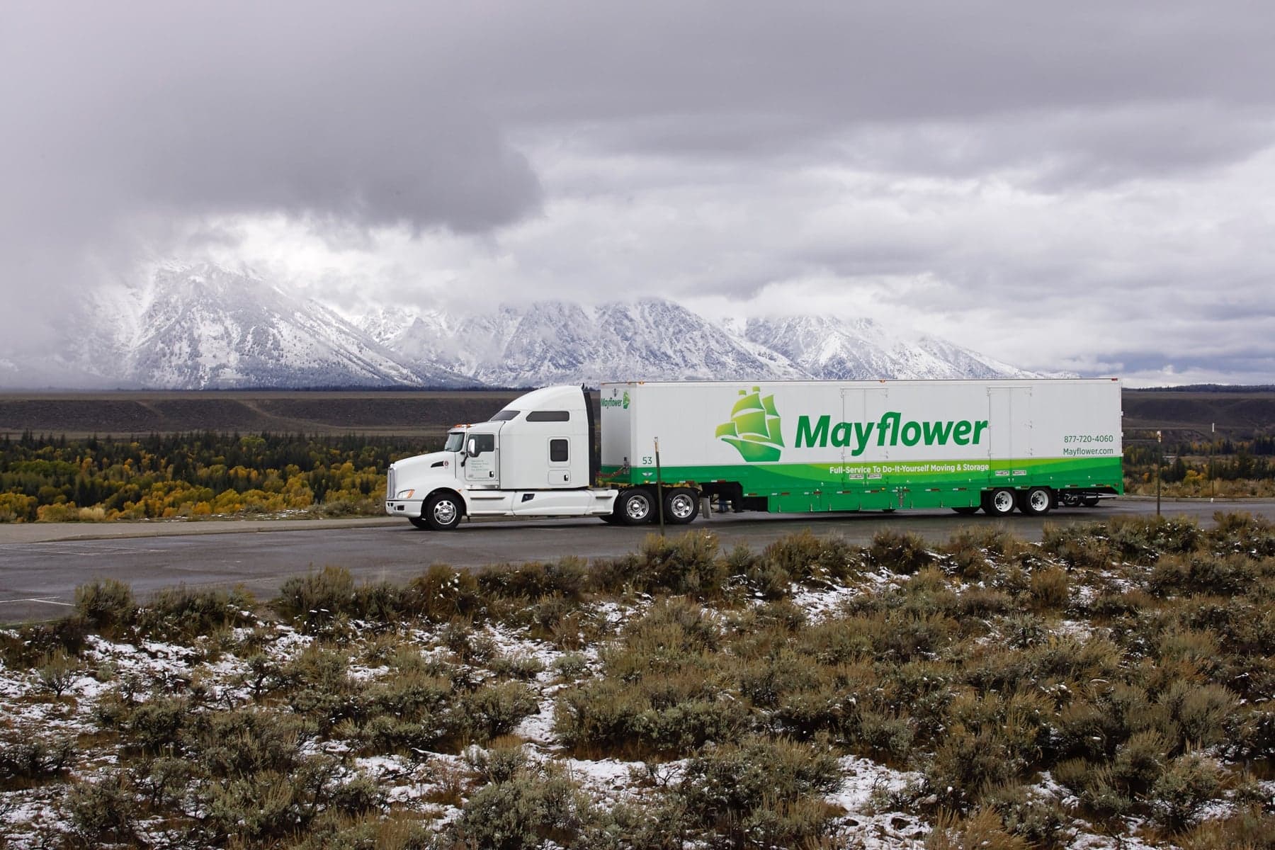 Mayflower moving truck on a highway with snowy mountains in the background