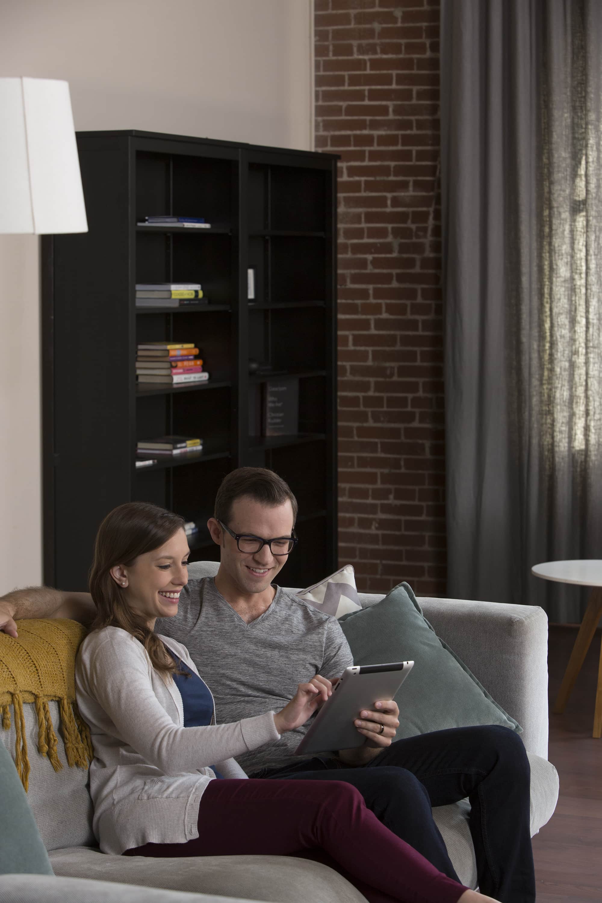young couple sitting on their couch planning their move on a tablet - Mayflower®