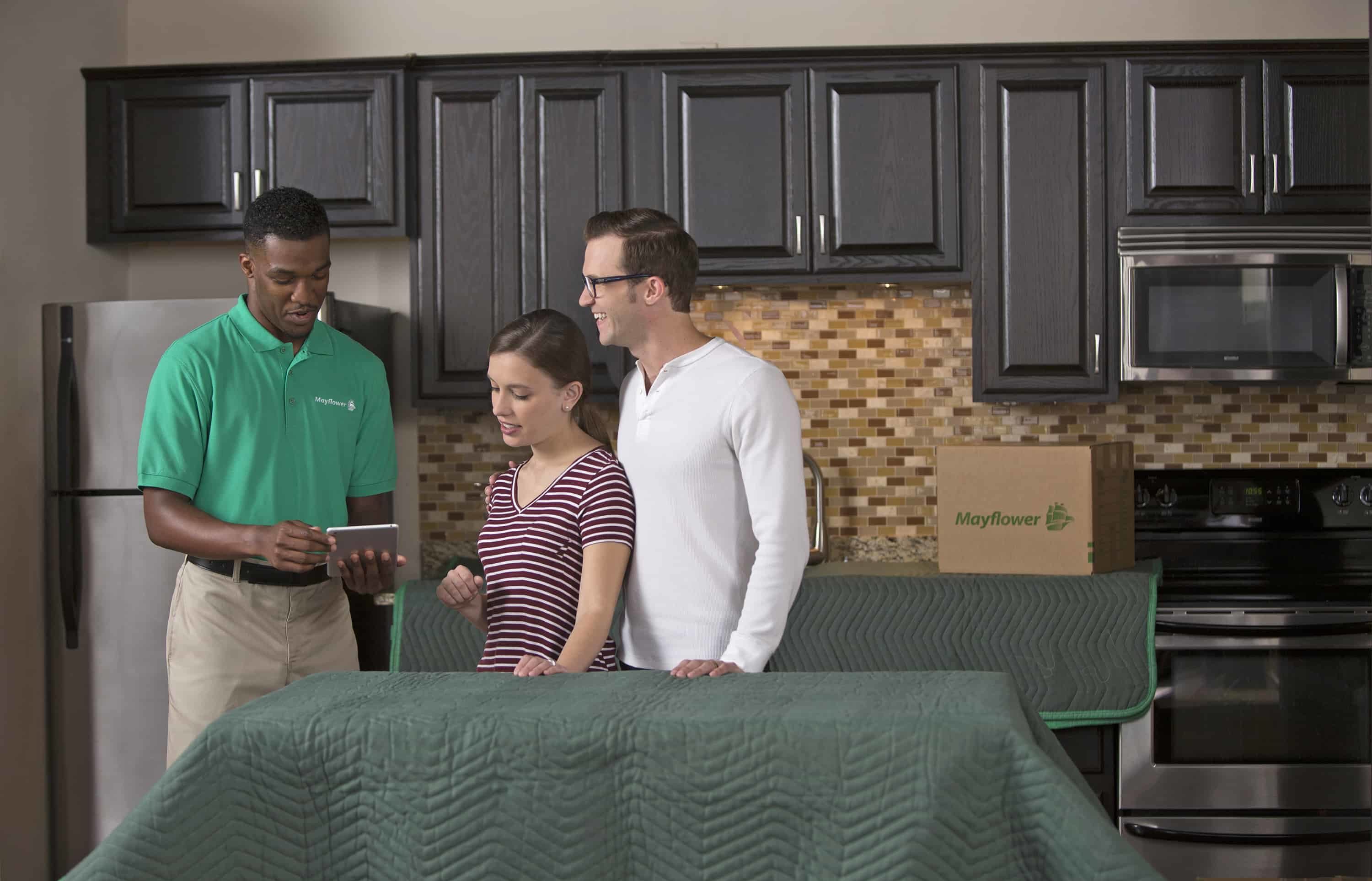 Young couple discussing moving plan with Mayflower mover in their kitchen - Mayflower