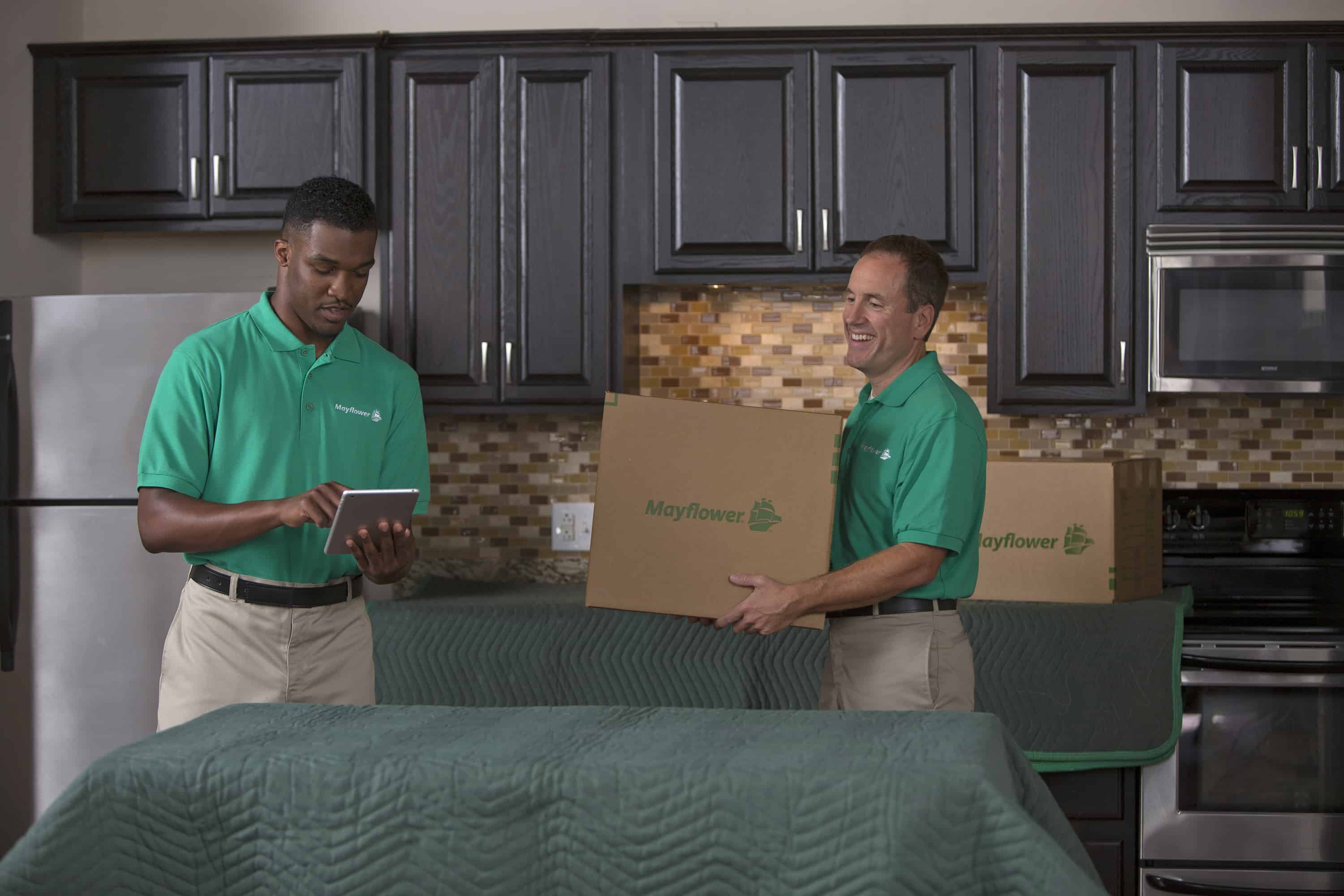 two packers checking their list on the tablet and carrying out boxes - Mayflower®