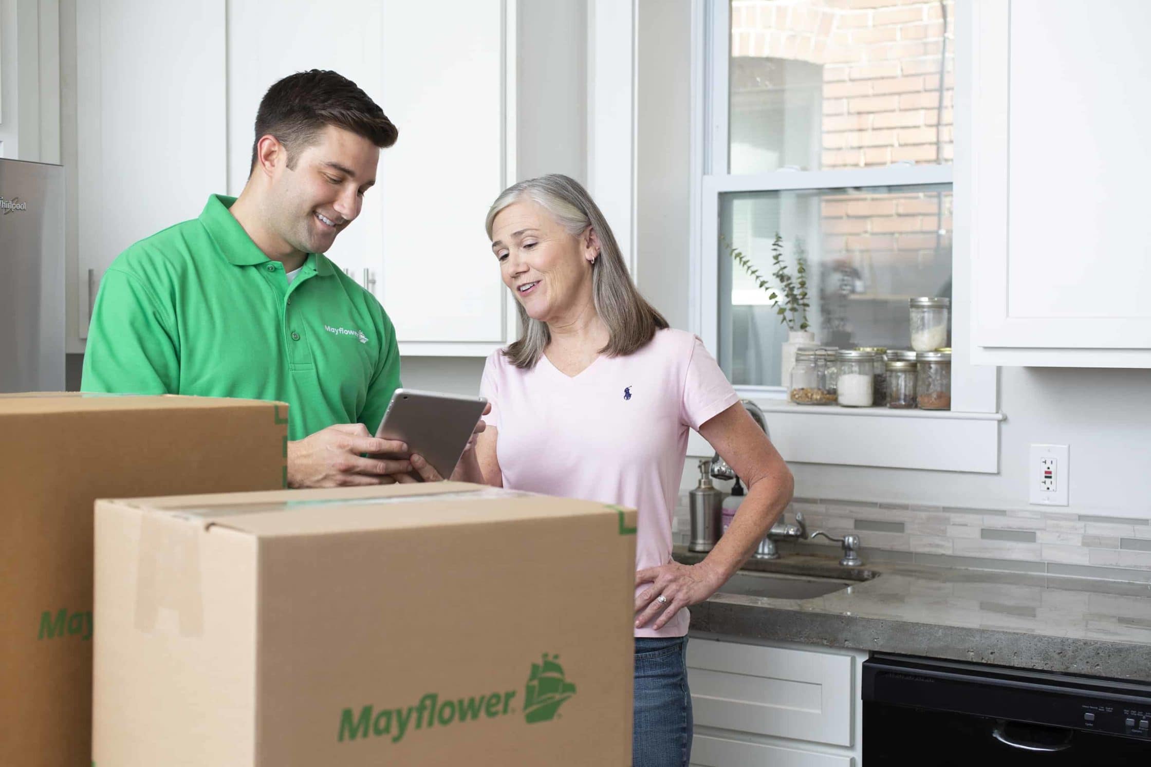 Male mover speaking with female customer in her kitchen- Mayflower