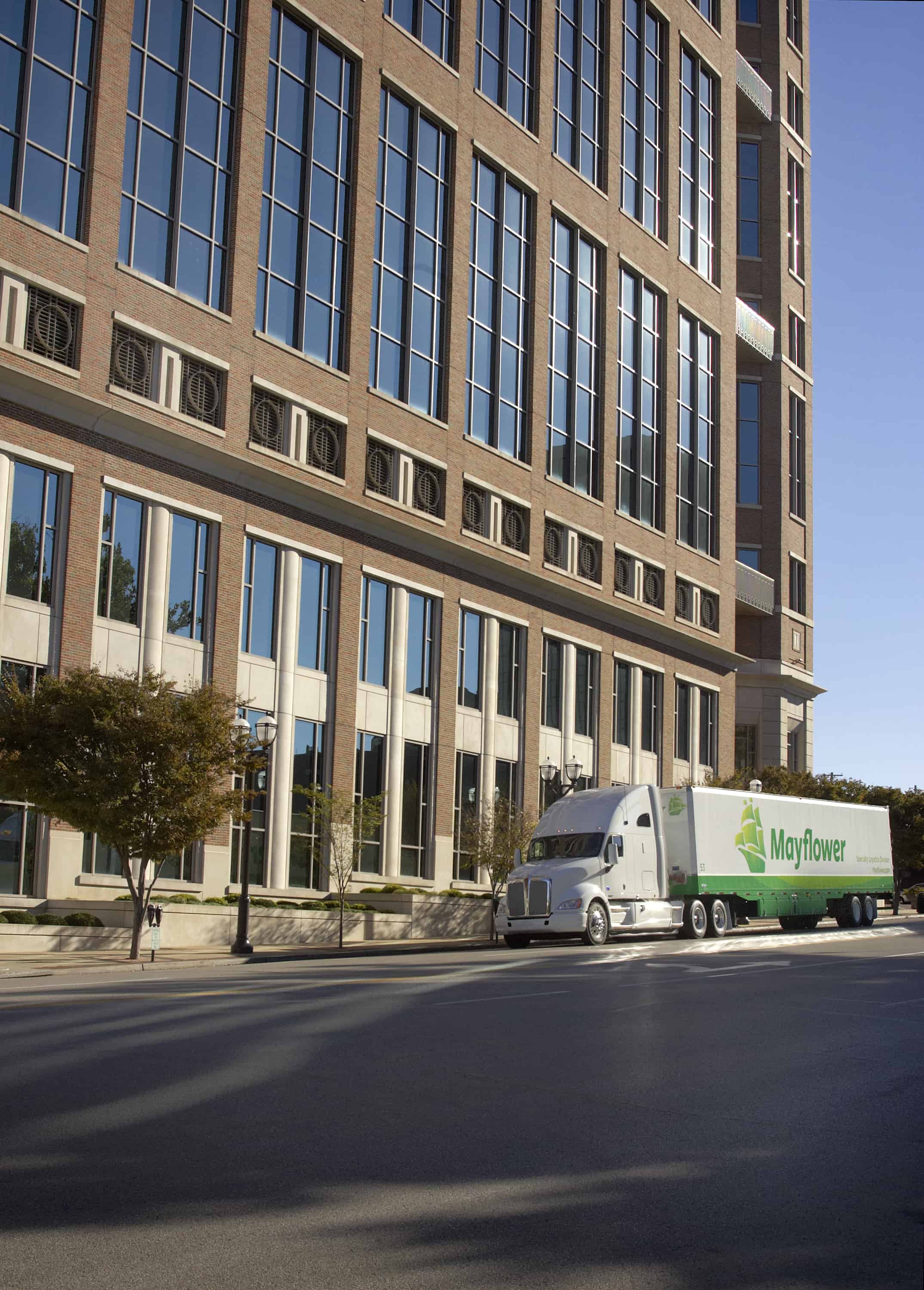Mayflower long distance moving truck driving next to office buildings