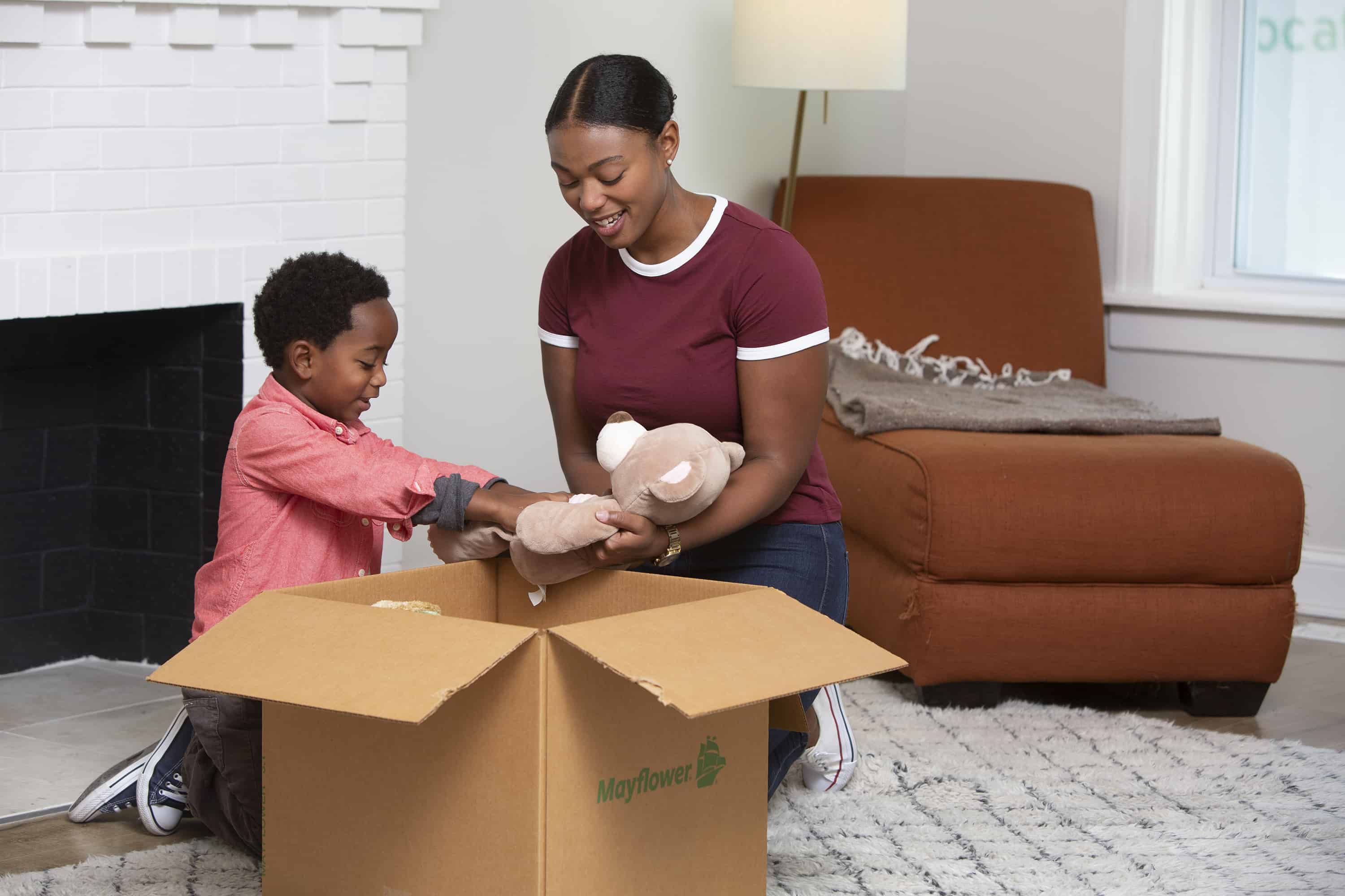 How to Pack the Living Room for Moving - mom and her young son packing up toys in their living room - Mayflower