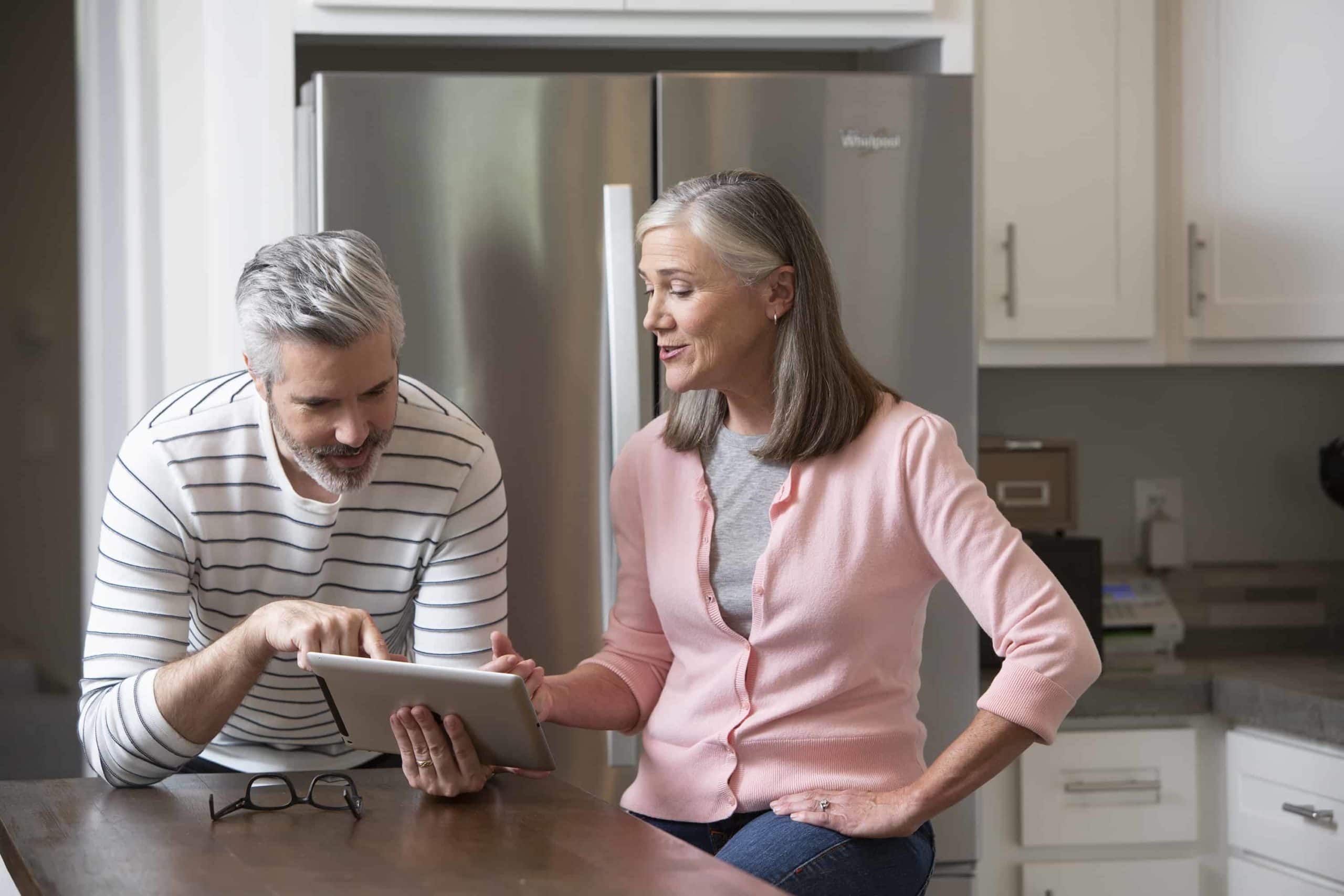 Baby boomer couple researching moving options on a tablet in their kitchen - Mayflower