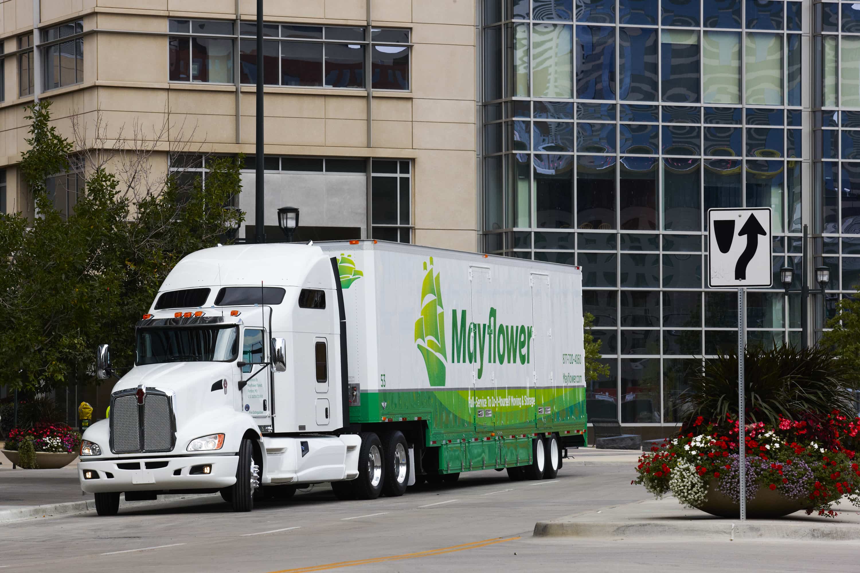 mayflower moving truck driving next to office buildings - Mayflower®