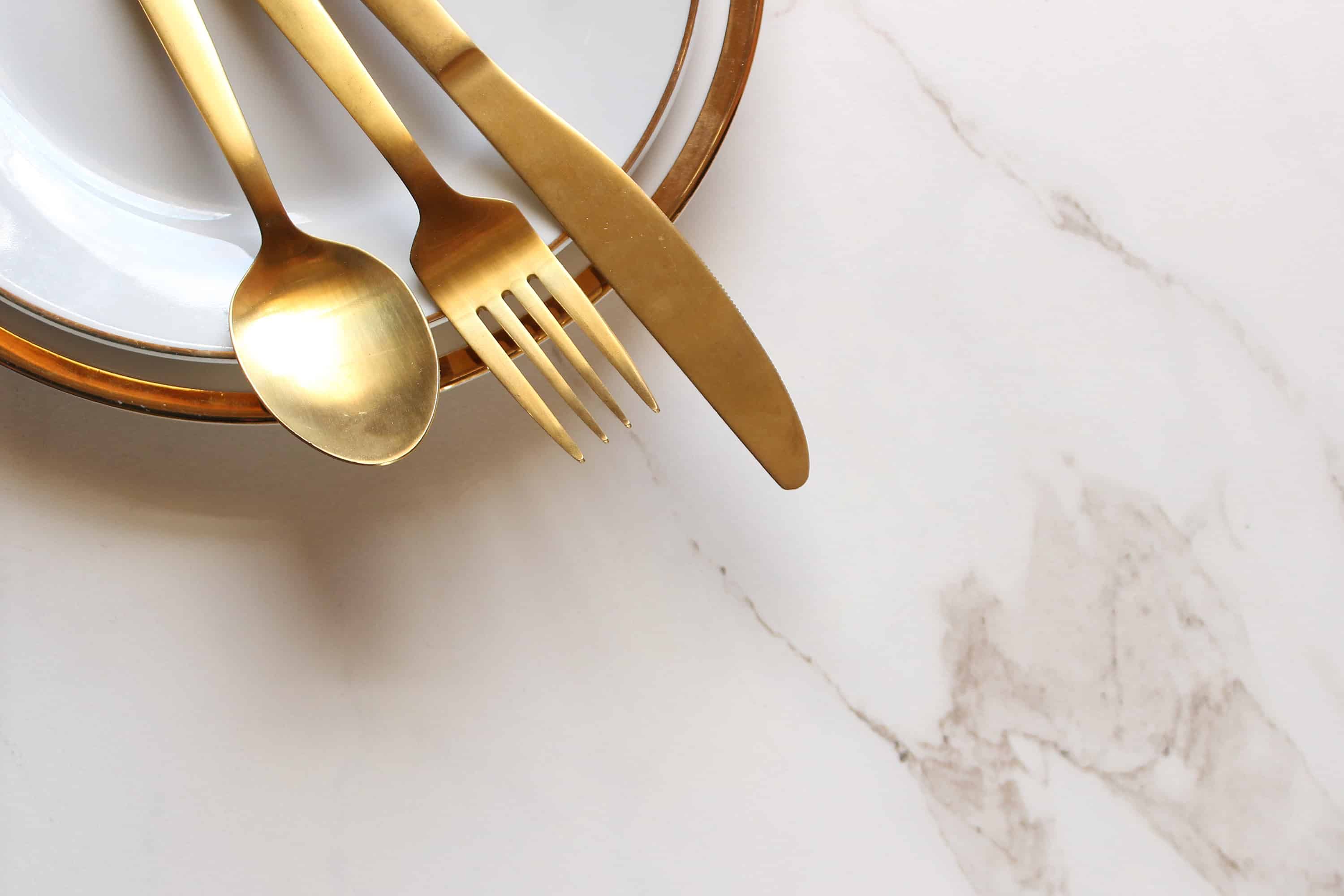 Modern gold and white place setting frames ample white marble copy space. - Mayflower®
